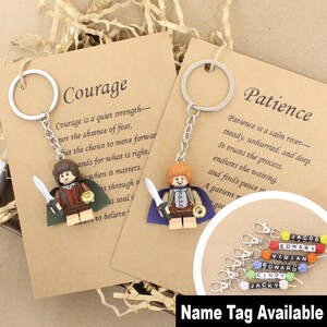 May include: Two keychains featuring miniature plastic figures with brown hair, capes, and swords attached to silver metal rings. Each is mounted on a tan card printed with the words Courage or Patience. A group of small name tags is also shown.