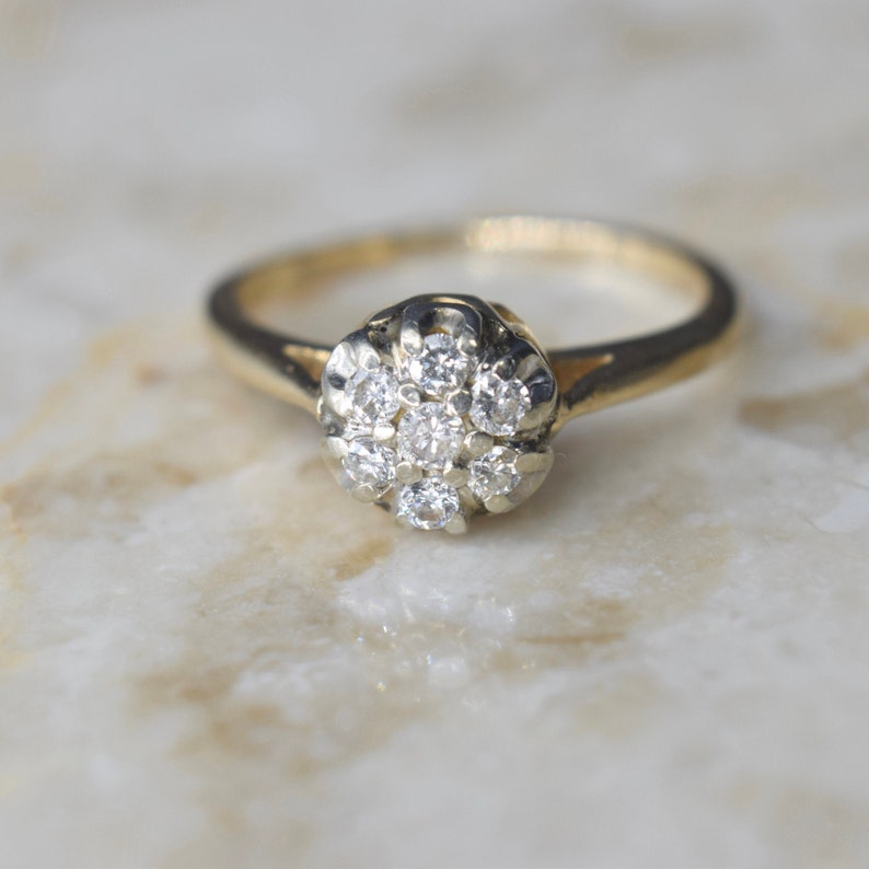 May include: A gold ring with a cluster of small diamonds set in a flower shape.