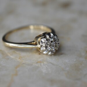 May include: A gold ring with a cluster of small diamonds set in a flower shape.