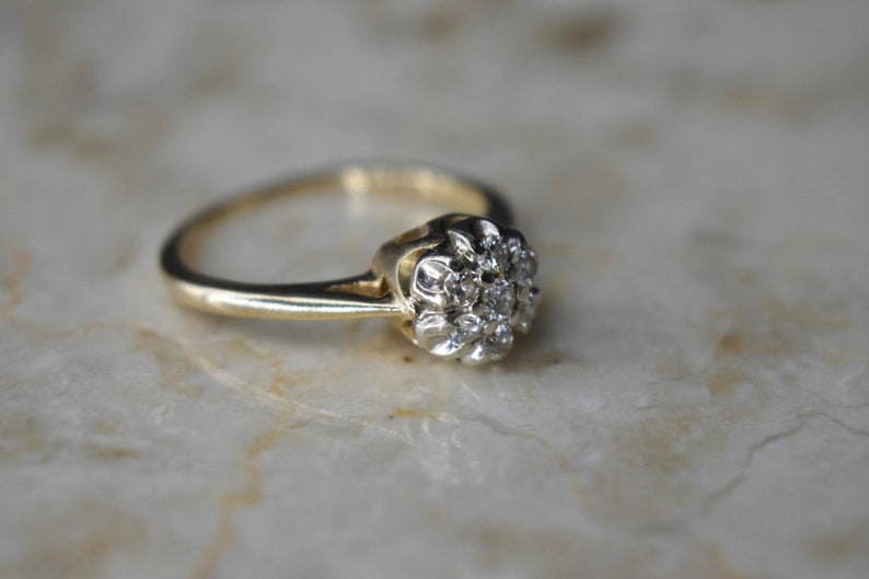 May include: A gold ring with a cluster of small diamonds set in a flower shape.