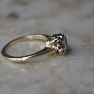 May include: A gold ring with a single, round diamond set in a delicate, ornate setting.