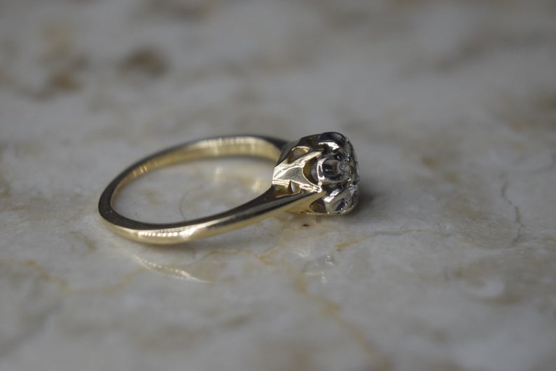 May include: A gold ring with a single, round diamond set in a delicate, ornate setting.