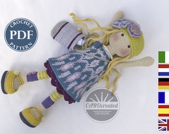 Può includere: Bambola all'uncinetto con lunghi capelli biondi che indossa un vestito viola e blu, scarpe gialle e un cappello verde e viola. La bambola tiene una piccola borsa all'uncinetto. L'immagine include anche un cerchio con il testo "CROCHET PDF PATTERN" e un cerchio con il testo "CAROcreated DESIGN".