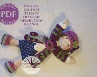 Può includere: Schema per bambola all'uncinetto in formato PDF, disponibile in inglese, tedesco, italiano, francese, olandese e spagnolo. La bambola indossa un maglione a righe viola e verde, una gonna blu con pois bianchi e un cappello viola con un fiore verde.