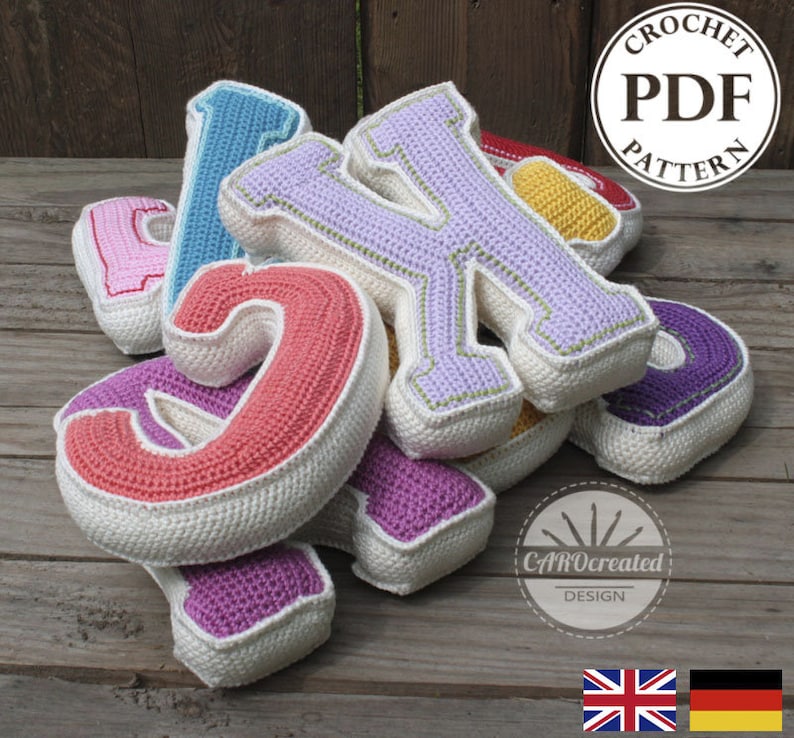 May include: A set of colorful crocheted letters, including pink, purple, blue, red, yellow, and green. The letters are stacked on top of each other and have a white border. The letters are on a wooden surface. The image also includes the text "CROCHET PDF PATTERN" and "CraftyCreated DESIGN".