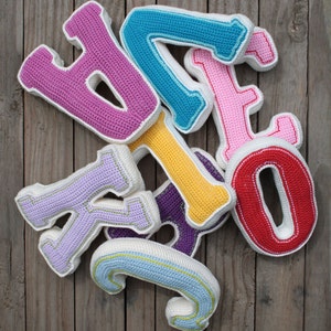 May include: A set of colorful crocheted letters, including a pink "B", a blue "I", a pink "G", a yellow "O", a purple "T", a red "O", a lavender "K", and a light blue "J".