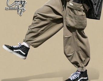 May include: Khaki-colored cargo pants with multiple pockets and a relaxed fit. The pants are paired with black high-top sneakers with white accents. The image also features the text "Comfy Pjs by Danica" in the upper left corner.