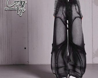 May include: Black denim wide-leg pants with distressed detailing. The pants feature a unique design with cut-out sections and decorative stitching. The text "Comfy by Danica" is in the upper left corner. The model is wearing a black and white striped top.