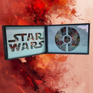 Peut inclure: Deux œuvres d'art encadrées sur le thème de Star Wars. Le cadre de gauche présente les mots "STAR WARS" découpés sur un fond clair. Le cadre de droite présente un motif circulaire. Le fond est un mélange de coups de peinture rouges et oranges.