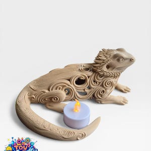 May include: A beige, decorative lizard figurine with intricate swirl patterns, holding a small, battery-operated candle with a flickering yellow light. The figurine is a unique home decor item.