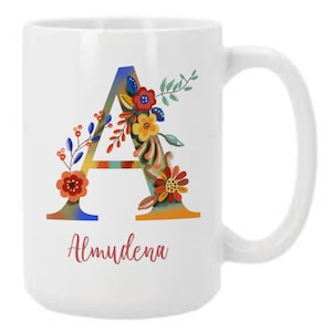 May include: White ceramic mug with a colorful floral design around the letter "A" and the name "Almudena" printed below.