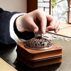 以下が含まれることがあります： 複雑なデザインが施された金属製の蓋が付いた木製の香炉。蓋の上には小さなノブがあり、香炉の側面には「ソフィア」という文字が刻まれています。