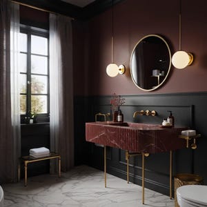 May include: A stylish bathroom featuring a red marble sink with gold fixtures and a circular mirror. The walls are painted in dark red and black, with a window on the left. The floor is white marble.