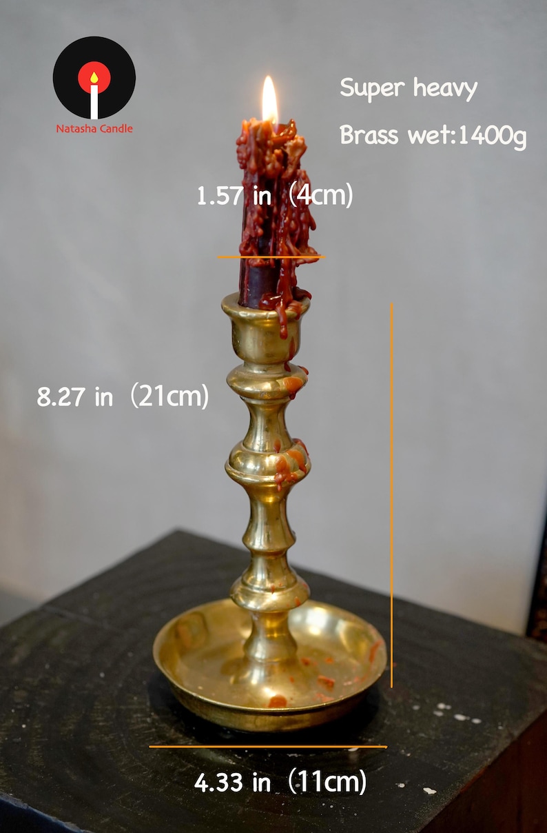 May include: A brass candlestick holder with a lit dark red candle featuring dripping wax. The holder is 8.27 inches tall with a 4.33 inch base diameter. The candle diameter is 1.57 inches. The brass weight is listed as 1400g. Text reads Natasha Candle.