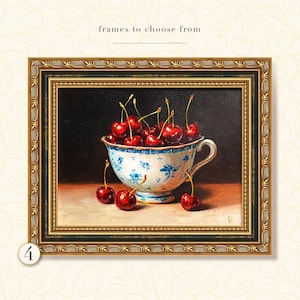 Puede incluir: Pintura enmarcada de naturaleza muerta con una taza llena de cerezas rojas. La taza tiene un dise&ntilde;o floral azul y blanco. El marco dorado adorna la pintura, con el texto "frames to choose from" en la parte superior.