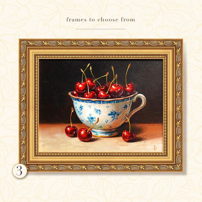 Puede incluir: Pintura enmarcada de cerezas en una taza de t&eacute; azul y blanca. Las cerezas son de color rojo intenso y la taza de t&eacute; tiene un dise&ntilde;o floral. El marco es dorado con detalles ornamentados. El texto en la parte superior dice "frames to choose from".