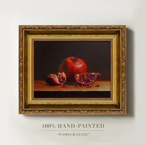 Peut inclure: Peinture à l'huile encadrée d'un cadre doré orné, représentant une grenade entière et deux moitiés. L'œuvre met en valeur les graines rouges du fruit. Le texte en bas indique "100% HAND-PAINTED" et "-POMEGRANATE-".