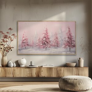Peut inclure: Peinture de paysage encadrée représentant une scène hivernale avec des arbres roses et blancs. L'œuvre présente un style doux et impressionniste avec un ciel rose clair et un sol enneigé. Le cadre en bois complète la palette de couleurs.