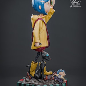 May include: A detailed figurine of a girl with blue hair wearing a yellow coat and boots, holding a green object. A black cat and a smaller figure are at her feet. The base is striped with black, green, and red.
