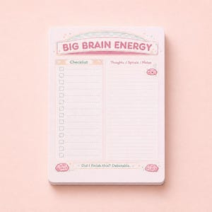 May include: A rectangular notepad with a light pink background featuring the text BIG BRAIN ENERGY at the top. The layout includes a left-hand checklist column and a right-hand lined section for notes, decorated with small pink brain illustrations.
