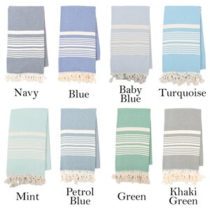 May include: Eight Turkish towels in various colors, including navy, blue, baby blue, turquoise, mint, petrol blue, green, and khaki green. Each towel has white stripes and fringe.