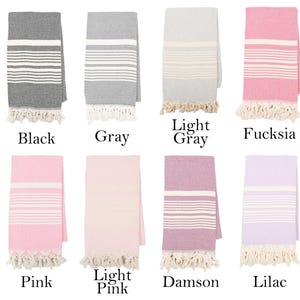 May include: Eight Turkish towels in different colors, including black, gray, light gray, fuchsia, pink, light pink, damson, and lilac. Each towel has white stripes and fringe.