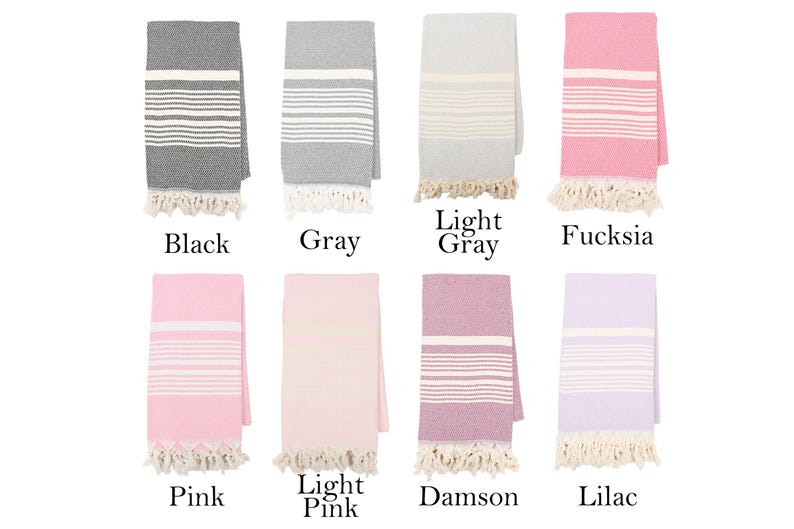 May include: Eight Turkish towels in different colors, including black, gray, light gray, fuchsia, pink, light pink, damson, and lilac. Each towel has white stripes and fringe.
