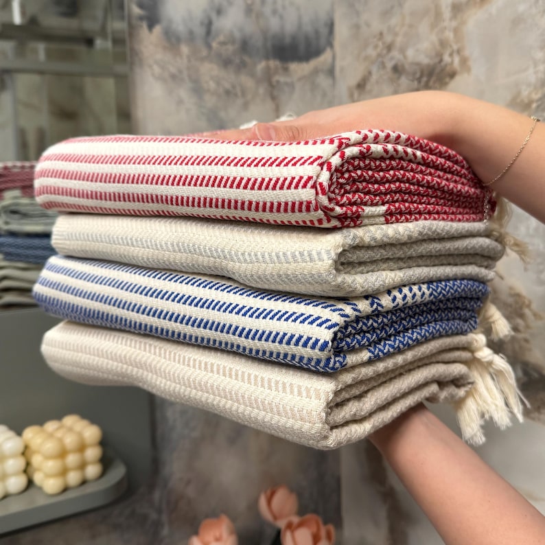 May include: A stack of four striped towels in red, white, and blue. The towels are folded and have tassels.