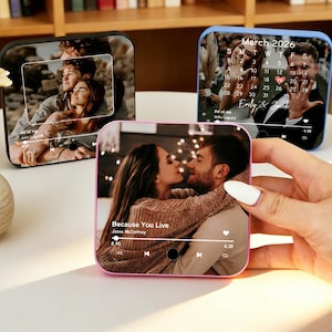 May include: Square personalized photo speakers with images of couples. One speaker has a pink frame and displays a couple embracing with the text "Because You Live". Another has a blue frame with a calendar.