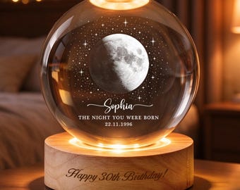 May include: A clear glass sphere lamp featuring an engraved moon and star pattern, the name Sophia, and the text THE NIGHT YOU WERE BORN 22.11.1996. The sphere rests on a round wooden base engraved with the text Happy 30th Birthday.