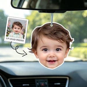 Könnte beinhalten: Ein Auto-Lufterfrischer mit dem Gesicht eines lächelnden Babys. Der Lufterfrischer hängt am Rückspiegel. Ein kleines Foto mit dem Text "UP LOAD PHOTO" ist ebenfalls zu sehen.