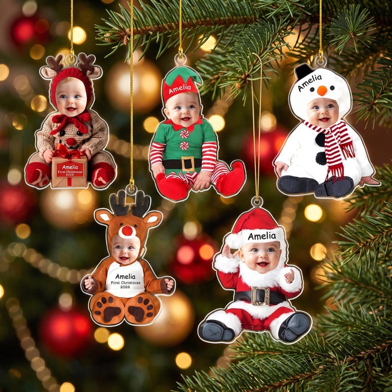 May include: Five personalized Christmas ornaments featuring photos of a baby in various costumes: a reindeer with a gift box labeled Amelia, an elf, a snowman, a reindeer with the text Amelia First Christmas 2026, and a Santa Claus with Amelia printed.