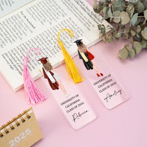 Puede incluir: Marcadores de acrílico transparente con borlas. Cada marcador presenta una ilustración de graduación y el texto "UNIVERSITY OF CALIFORNIA CLASS OF 2026" con un nombre. Borlas rosas, amarillas y rosas.
