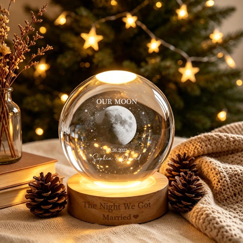 May include: A clear glass sphere lamp on a round wooden base. The sphere features an etched moon, the text "OUR MOON", "09.26.2023", and "Sophia & David". The wooden base is engraved with "The Night We Got Married" and a heart symbol.