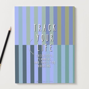 Puede incluir: Un cuaderno con un patrón de rayas azules, verdes y grises. El texto "TRACK YOUR LIFE" se muestra en blanco, junto con las palabras "CHECKLISTS, PLANNERS, AND PAGES FOR DOODLING". Un lápiz negro con punta dorada está a la izquierda.