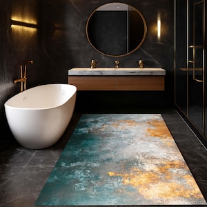 May include: A rectangular area rug featuring an abstract design with blended shades of teal, deep blue, white, and metallic gold. The surface texture appears weathered and mottled, creating a gradient effect across the floor covering.