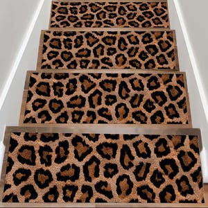 Puede incluir: Peldaños de escalera con diseño de estampado de leopardo. Los peldaños tienen un fondo marrón con manchas negras y marrones. Están instalados en escaleras de madera con paredes blancas a ambos lados.