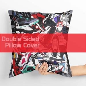 May include: A double-sided pillow cover featuring a collage of colorful sneakers in various styles. The design includes red, black, white, and blue shoes. The text "Double Sided Pillow Cover" is displayed across the center in a red banner.