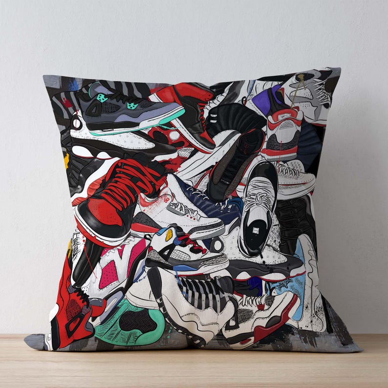 May include: A decorative throw pillow featuring a vibrant collage of sneakers in various colors and styles. The design includes red, black, white, and blue athletic shoes, creating a dynamic and modern aesthetic. The pillow is square-shaped.