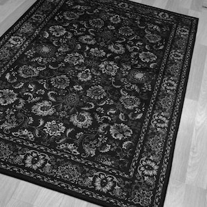 May include: Black and white area rug with a floral pattern. The rug features a dark background with a repeating design of stylized flowers and leaves in lighter shades. A decorative border frames the rug.