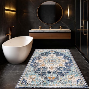 Può includere: Un tappeto rettangolare a fantasia in un ambiente bagno. Il tappeto presenta un motivo a medaglione centrale con sfumature di blu, crema e arancione. Il bagno ha una vasca da bagno bianca, un mobile lavabo in legno e un grande specchio rotondo. Misura circa 150 cm x 90 cm.