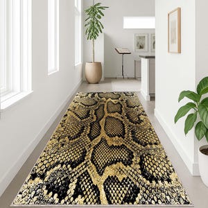 Peut inclure: Un tapis rectangulaire avec un motif peau de serpent en noir et or. Le tapis est placé dans un couloir avec des murs blancs et une plante en pot. Le motif imite la peau d'un reptile.