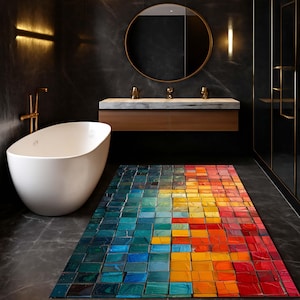 May include: A modern bathroom with a white oval bathtub, a wooden vanity with a marble countertop, and a colorful rug. The rug features a mosaic design with squares of blue, green, yellow, orange, and red. A round mirror hangs above the vanity.