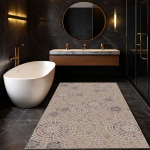 Könnte beinhalten: Ein rechteckiger Badezimmerteppich mit einem kreisförmigen Mosaikmuster in Beige-, Grau- und Brauntönen. Der Teppich liegt auf einem dunkelgrauen Fliesenboden in einem modernen Badezimmer. Eine weiße Badewanne und ein Holzwaschtisch sind ebenfalls zu sehen.