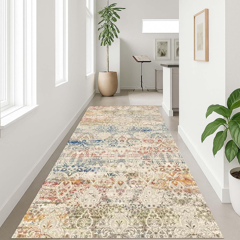 May include: A rectangular area rug with a distressed, vintage-inspired design. The rug features a mix of colors including cream, blue, red, and gold. The pattern includes floral and geometric elements, creating a layered, textured look. The rug is placed in a hallway.