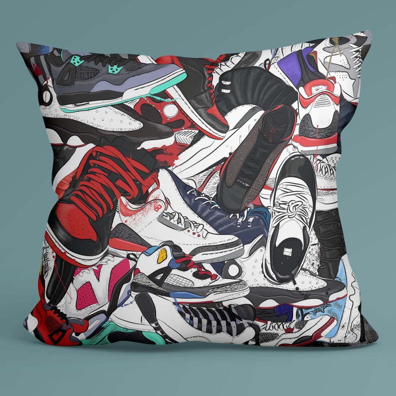 May include: A square pillow featuring a colorful collage of sneakers in various styles and colors. The design includes red, black, white, and blue shoes, creating a vibrant and eye-catching pattern. The pillow is a decorative item for home decor.