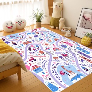 Può includere: Un colorato tappeto gioco per bambini con un design a mappa stradale. Il tappeto presenta strade, edifici, veicoli e illustrazioni fantasiose nelle tonalità del viola, rosa, blu e verde. Il tappeto misura circa 152 cm per 203 cm.