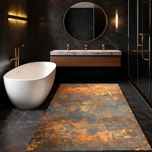 Op de afbeelding: Een moderne badkamer met een witte ovale badkuip, een houten wastafel met een marmeren blad en een grote ronde spiegel. Een rechthoekig tapijt met een roestig oranje en blauw patroon bedekt de vloer. De donkere muren creëren een luxe sfeer.