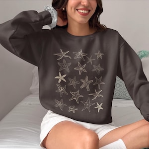May include: A dark grey sweatshirt with a pattern of beige starfish printed on the front.