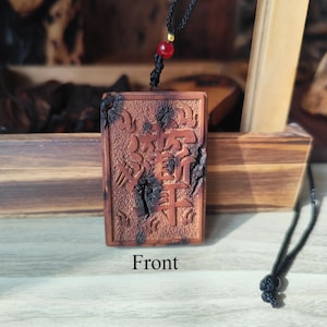 May include: A rectangular, brown wooden pendant with carved Chinese characters. The pendant hangs from a black cord with a red bead and a knot. The word "Front" is printed at the bottom of the image.